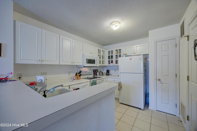 kitchen featuring light tile patterned flooring, white cabinetry, sink, white appliances, and a textured ceiling