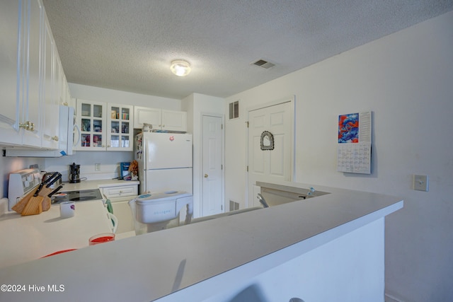 kitchen with stainless steel range with electric cooktop, white cabinetry, a textured ceiling, white refrigerator, and kitchen peninsula