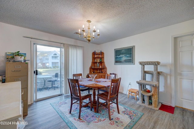 dining room featuring a textured ceiling, a chandelier, and light wood-type flooring