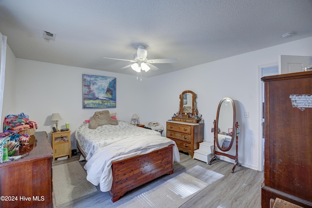 bedroom featuring ceiling fan, light hardwood / wood-style flooring, and a textured ceiling