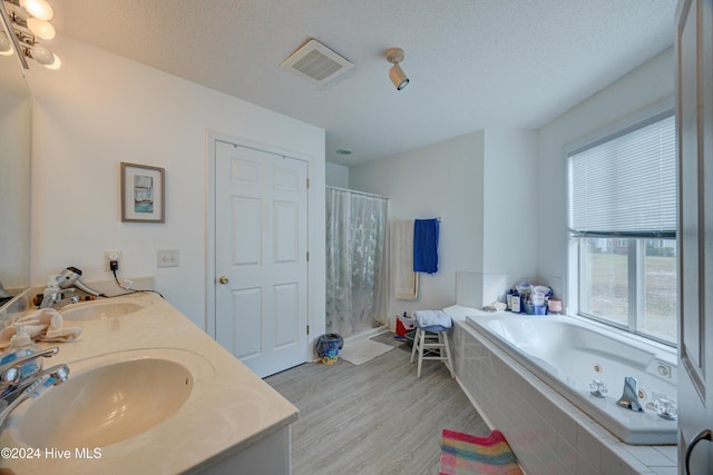 bathroom with hardwood / wood-style flooring, vanity, a textured ceiling, and plus walk in shower