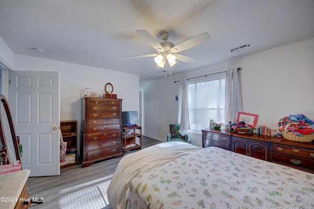 bedroom featuring ceiling fan, light hardwood / wood-style floors, and a textured ceiling