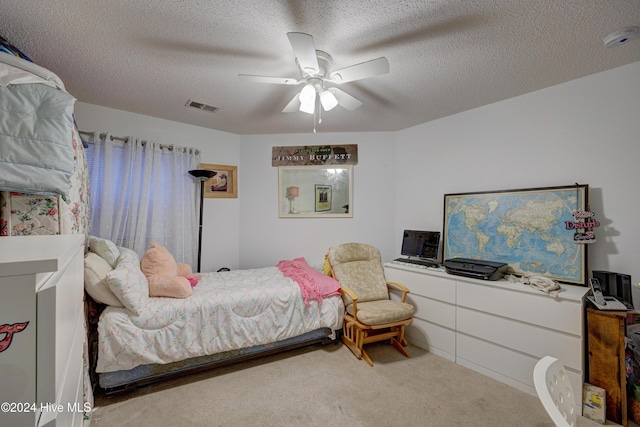 carpeted bedroom with ceiling fan and a textured ceiling