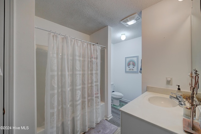 full bathroom with shower / tub combo with curtain, vanity, a textured ceiling, and toilet