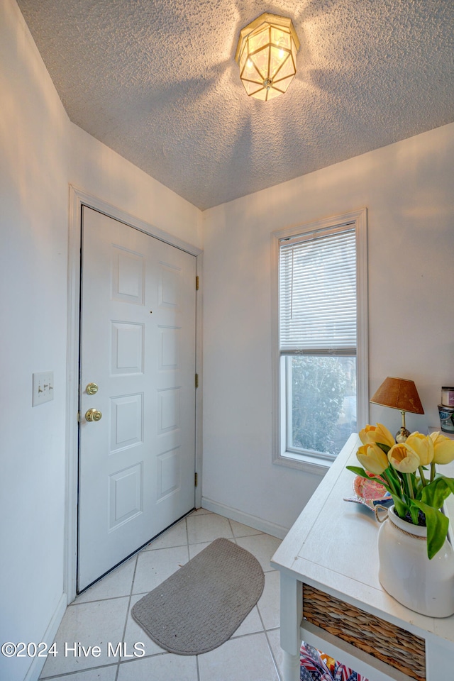 foyer entrance with light tile patterned flooring and a textured ceiling