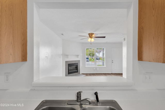 kitchen featuring ceiling fan, a fireplace, and sink