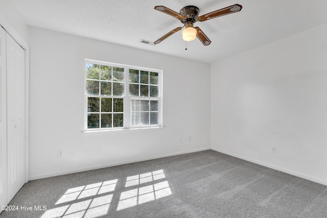 carpeted spare room with ceiling fan and a textured ceiling