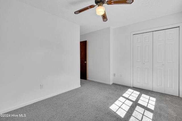 unfurnished bedroom featuring ceiling fan, light carpet, and a closet