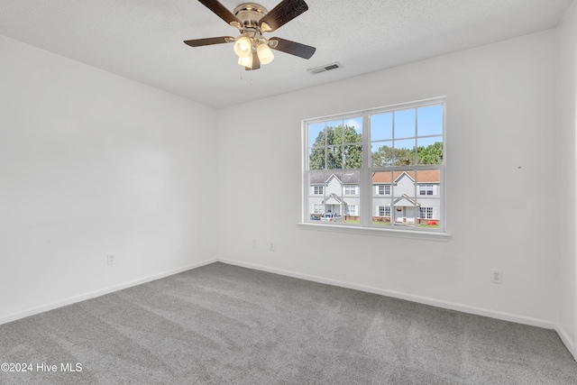 carpeted spare room with ceiling fan and a textured ceiling