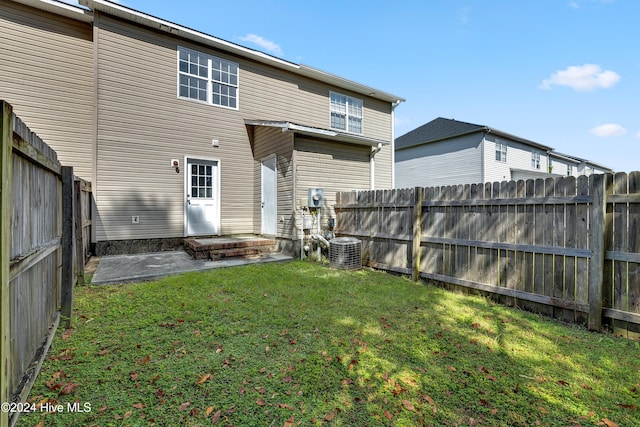 back of property featuring central air condition unit and a lawn