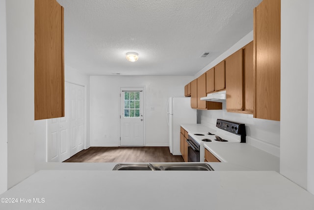 kitchen featuring hardwood / wood-style floors, white appliances, and a textured ceiling