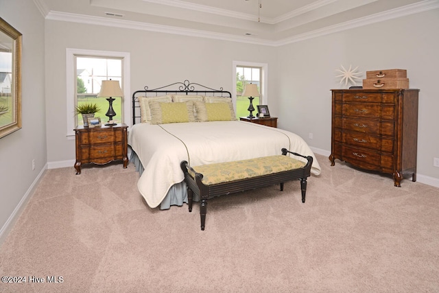 bedroom with light colored carpet, a tray ceiling, and ornamental molding