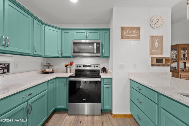 kitchen with green cabinets, light stone counters, light wood-type flooring, and stainless steel appliances