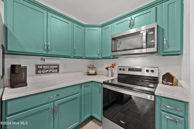 kitchen with light stone countertops, appliances with stainless steel finishes, light hardwood / wood-style flooring, and green cabinetry