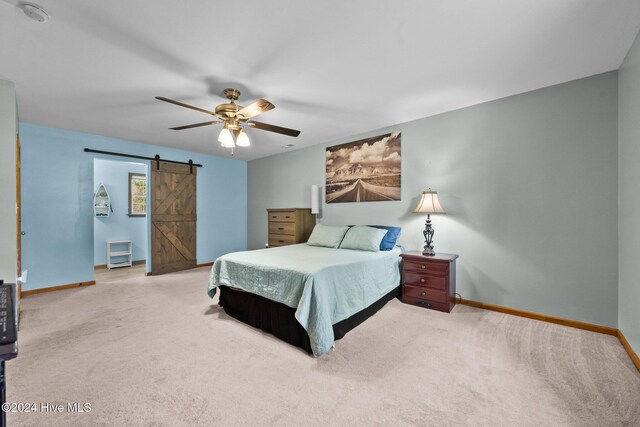 carpeted bedroom featuring a barn door and ceiling fan