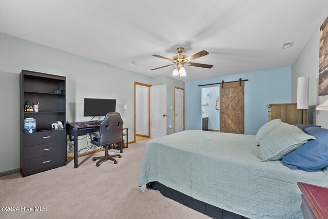 bedroom with a barn door, ceiling fan, and light carpet