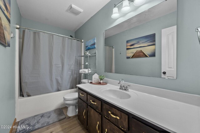 full bathroom featuring hardwood / wood-style flooring, vanity, toilet, and shower / bathtub combination with curtain