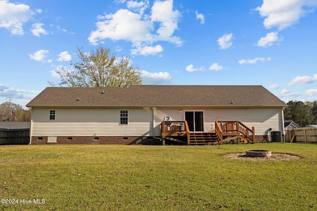 back of property with a lawn, a wooden deck, and a fire pit