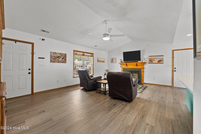 living room with light hardwood / wood-style floors, vaulted ceiling, and ceiling fan