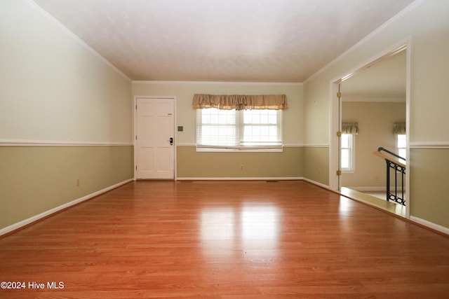 empty room with hardwood / wood-style flooring and crown molding