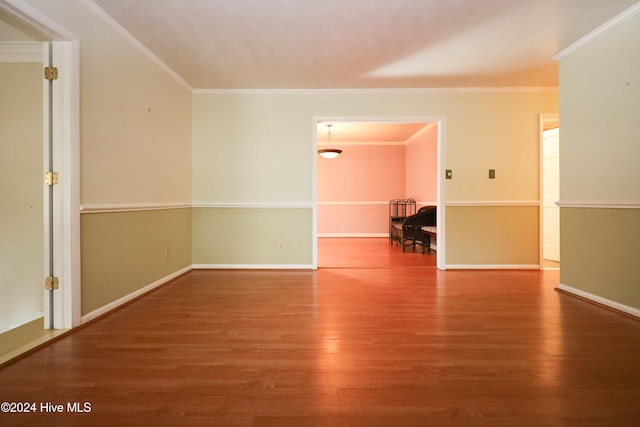 spare room featuring wood-type flooring and crown molding