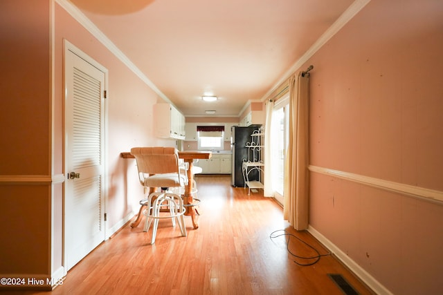 hall with light hardwood / wood-style floors and ornamental molding