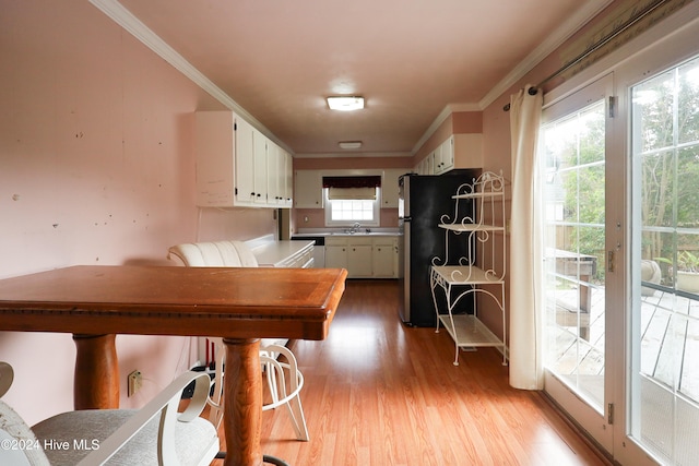 kitchen featuring crown molding, sink, white cabinets, light hardwood / wood-style floors, and stainless steel refrigerator