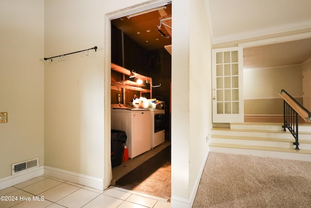 corridor featuring washing machine and dryer and light tile patterned floors