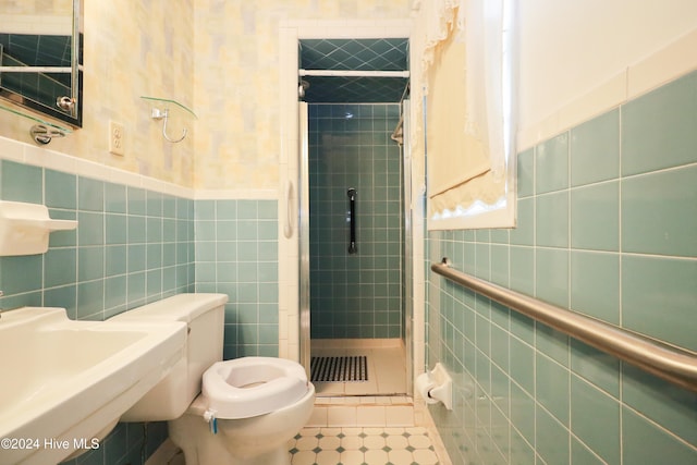 bathroom featuring tile patterned floors, a tile shower, sink, tile walls, and toilet