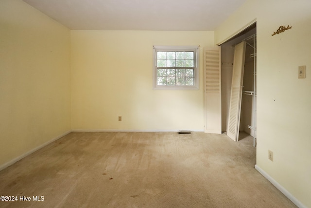 unfurnished bedroom featuring light carpet and a closet