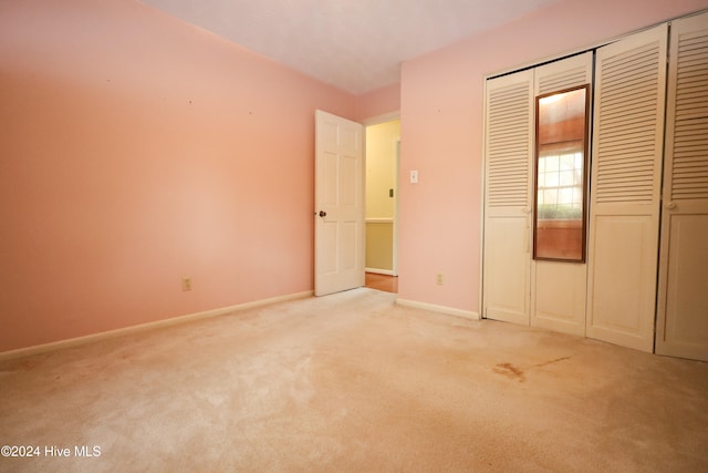 unfurnished bedroom with light carpet and a closet