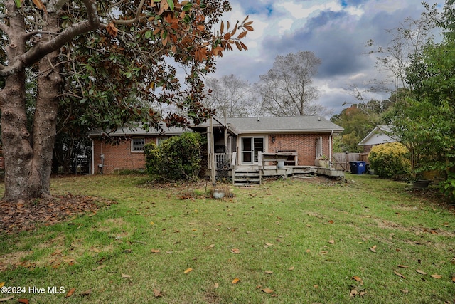 back of property featuring a lawn and a wooden deck