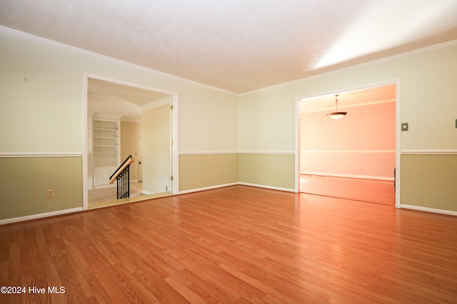 spare room featuring wood-type flooring and ornamental molding