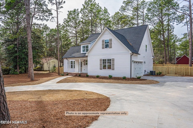 modern inspired farmhouse featuring driveway, a garage, fence, and cooling unit