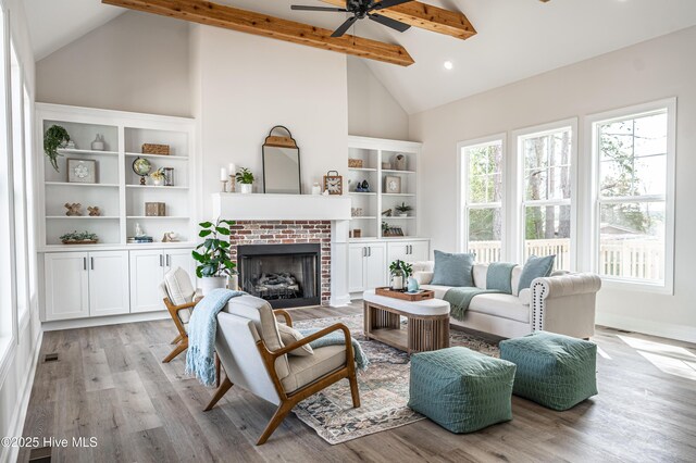 unfurnished living room featuring beam ceiling, a fireplace, a ceiling fan, wood finished floors, and baseboards