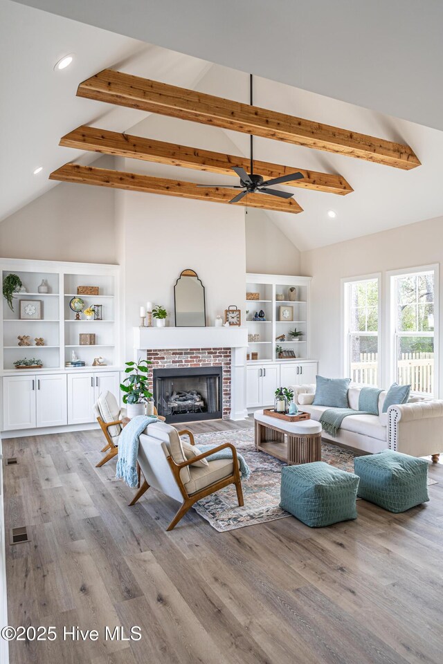 unfurnished living room featuring beam ceiling, a fireplace, baseboards, and wood finished floors