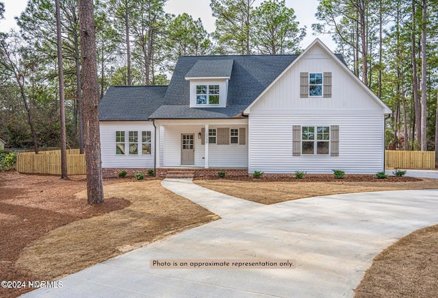 modern farmhouse style home featuring a shingled roof and fence