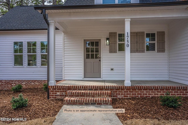 view of exterior entry featuring a porch and roof with shingles