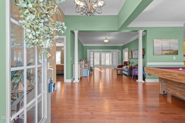 entrance foyer with decorative columns, an inviting chandelier, and ornamental molding