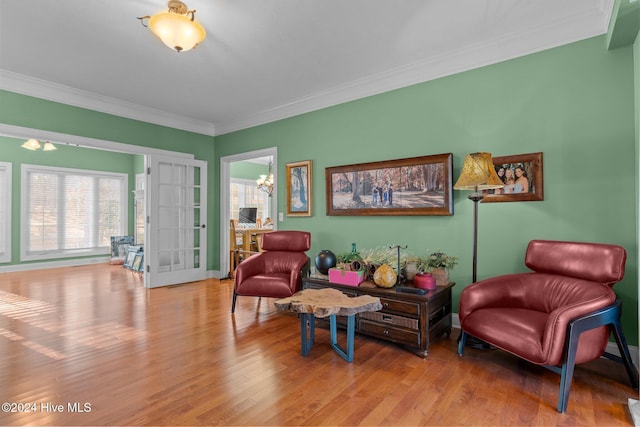 living area featuring a healthy amount of sunlight, an inviting chandelier, french doors, and light hardwood / wood-style flooring