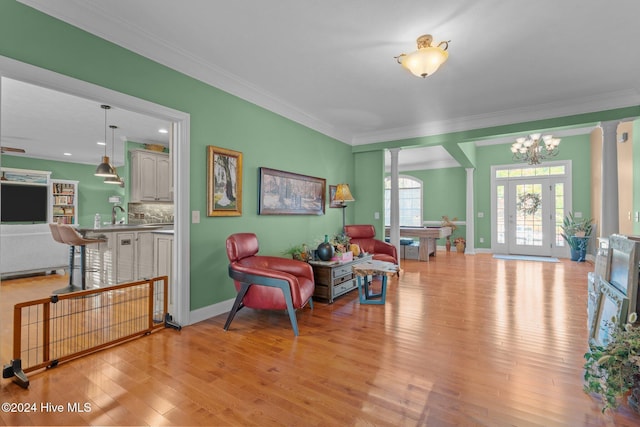 sitting room with a chandelier, light hardwood / wood-style flooring, ornate columns, and ornamental molding