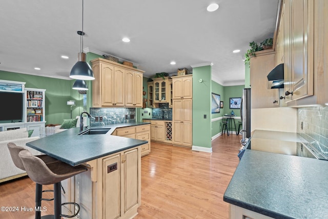 kitchen with hanging light fixtures, sink, light wood-type flooring, and light brown cabinets