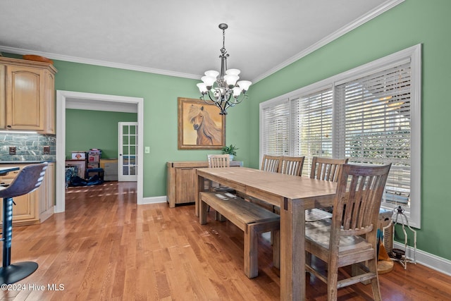 dining space with light hardwood / wood-style flooring, ornamental molding, and a notable chandelier