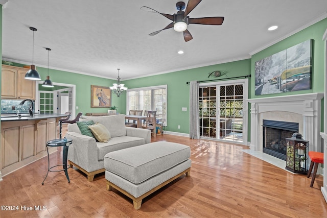 living room with sink, ornamental molding, ceiling fan with notable chandelier, and light hardwood / wood-style flooring