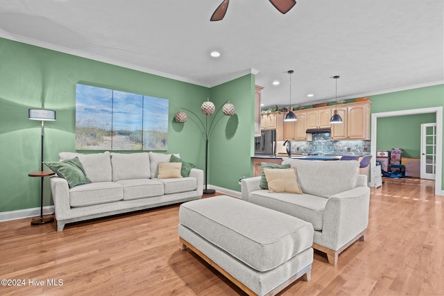 living room featuring ceiling fan, ornamental molding, and light wood-type flooring