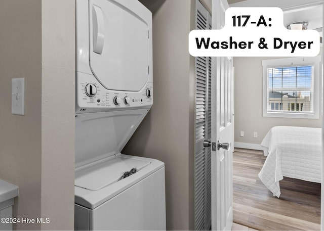 laundry room featuring light wood-type flooring, stacked washer / drying machine, laundry area, and baseboards