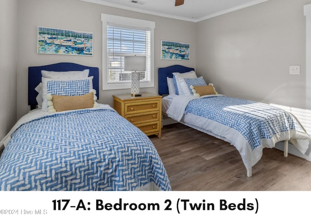 bedroom featuring a ceiling fan, visible vents, ornamental molding, and wood finished floors