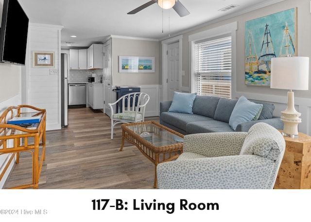 living room with ornamental molding, wood finished floors, visible vents, and a ceiling fan