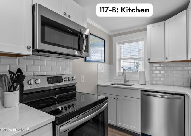 kitchen with ornamental molding, appliances with stainless steel finishes, a sink, and white cabinetry