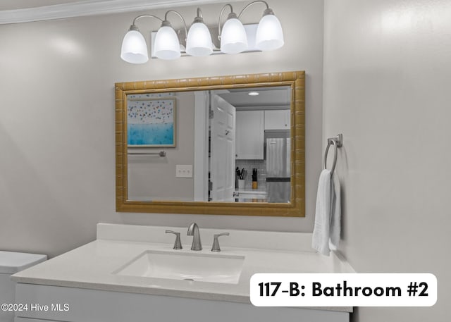 bathroom with toilet, ornamental molding, and vanity